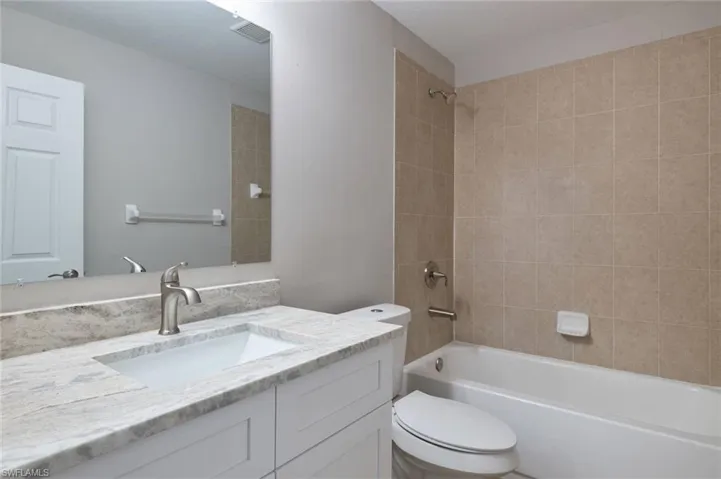 Full bathroom with toilet, vanity, and tiled shower / bath