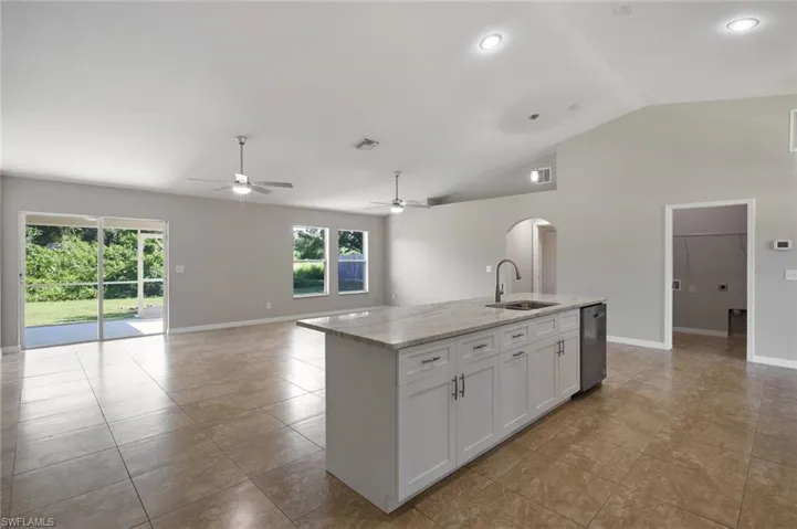 Kitchen with white cabinetry, light tile patterned flooring, ceiling fan, sink, and a center island with sink