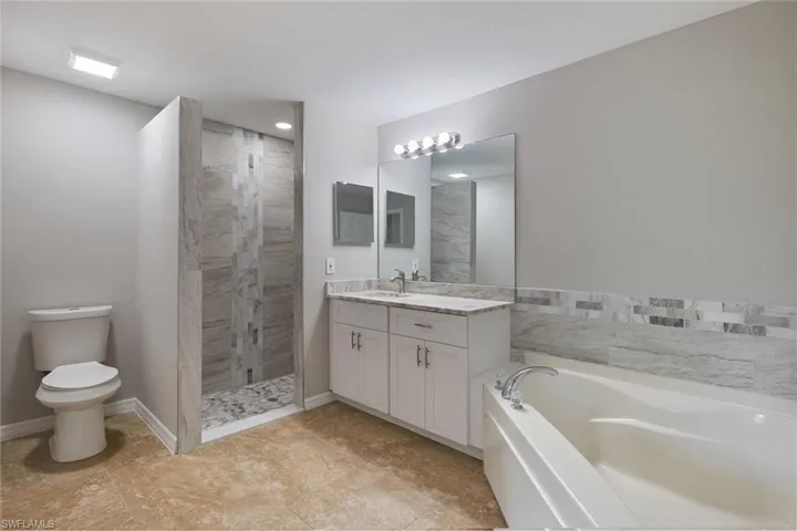 Full bathroom with vanity, toilet, tile patterned floors, and shower with separate bathtub