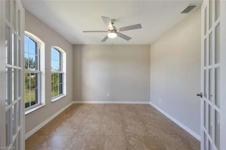 Empty room featuring tile patterned flooring, ceiling fan, and french doors