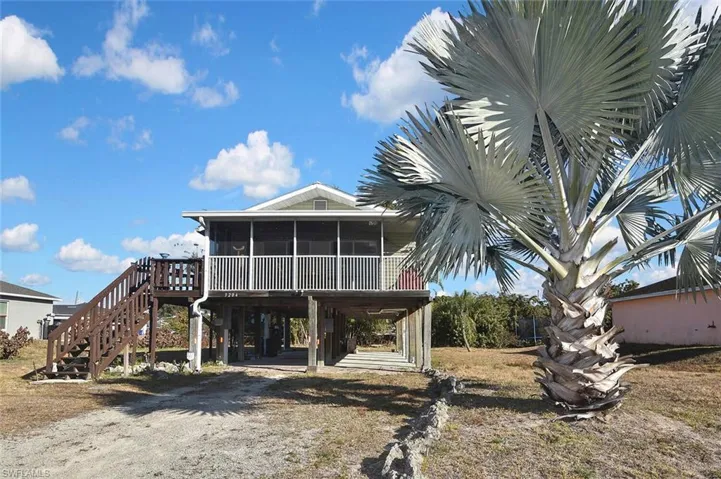 Back of house with a sunroom, a deck, a carport, and driveway