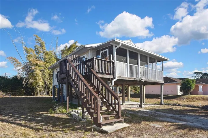 Back of house featuring a wooden deck, a sunroom, and a yard