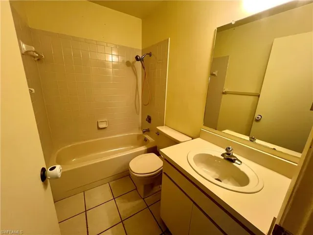 Full bathroom featuring tile flooring, tiled shower / bath, oversized vanity, and toilet
