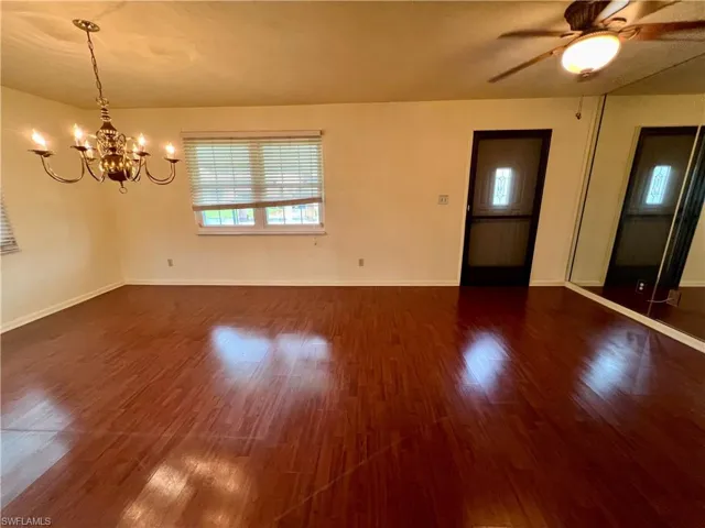 Dining room featuring dark wood-type flooring and ceiling fan with notable chandelier