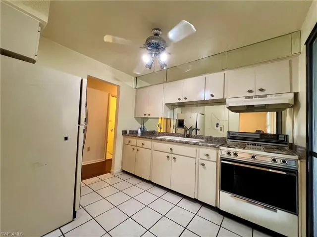 Kitchen with ceiling fan, white appliances, light wood-type flooring, sink, and white cabinetry