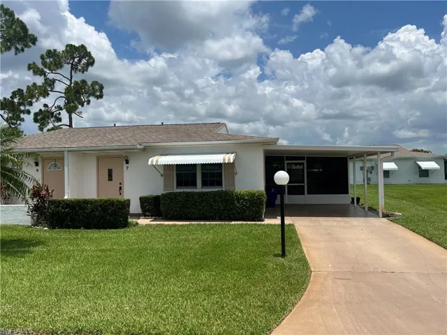 View of front facade featuring a carport and a front yard