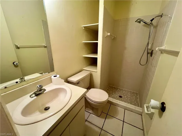 Bathroom featuring tile floors, a tile shower, toilet, and vanity