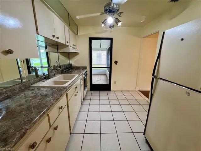 Kitchen featuring light tile floors, white cabinetry, range with gas cooktop, and white refrigerator