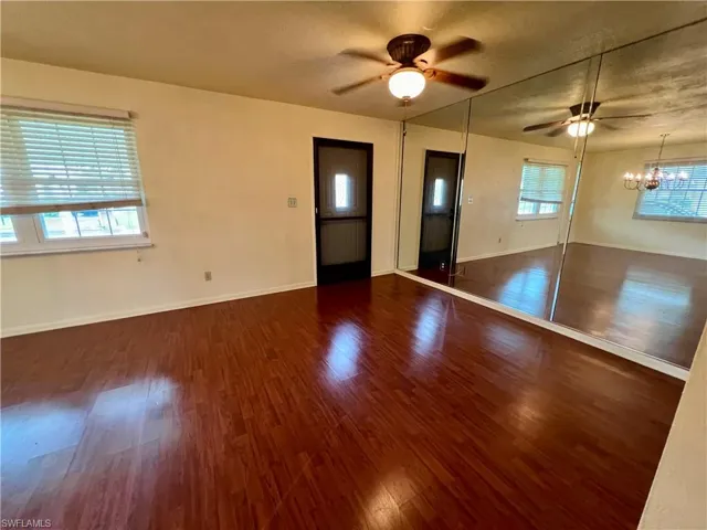Living room featuring a wealth of natural light, dark hardwood / wood-style floors, and ceiling fan with notable chandelier