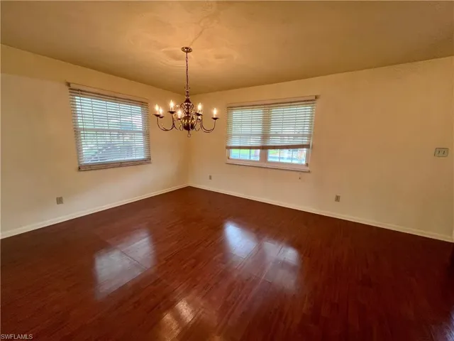 Unfurnished room with a chandelier and dark hardwood / wood-style floors