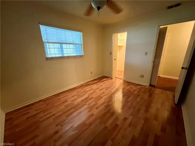 Guest bedroom featuring ceiling fan, a closet, crown molding, and wood-type flooring