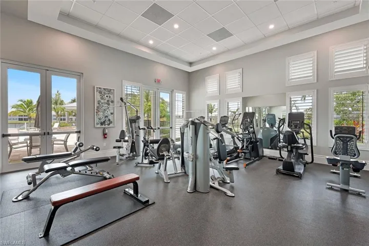 Workout area featuring french doors, a high ceiling, baseboards, recessed lighting, and a paneled ceiling