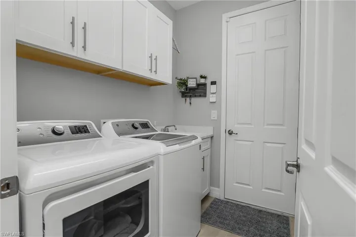 Laundry room with gas dryer, utility sink, and additional cabinetry for extra storage.