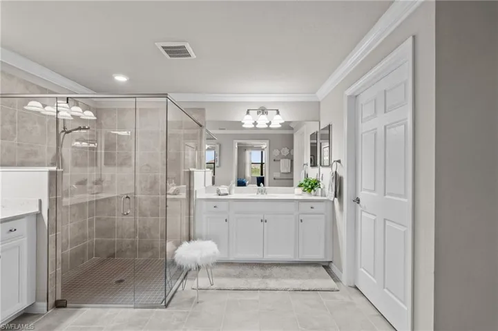 Full bathroom featuring a stall shower, crown molding, vanity, a chandelier, and visible vents