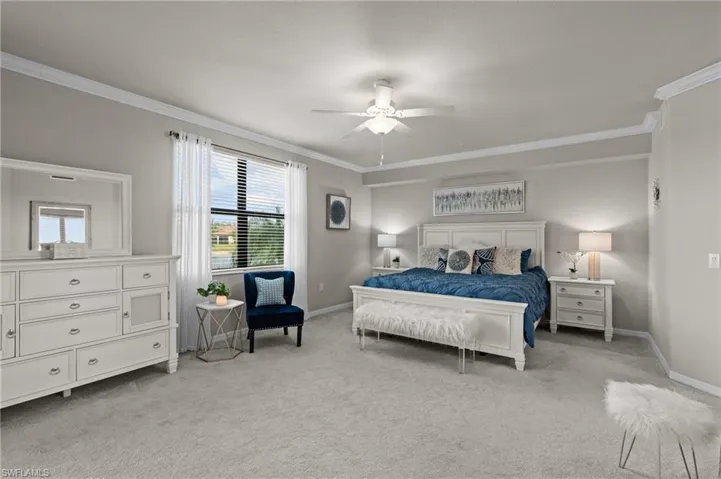Bedroom with a ceiling fan, light carpet, crown molding, and baseboards