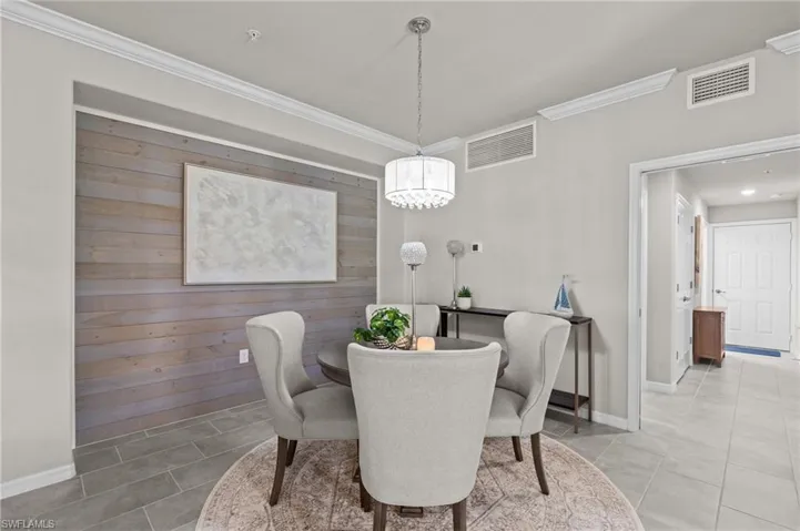 Dining space with ornamental molding, visible vents, tile patterned flooring, and a notable chandelier