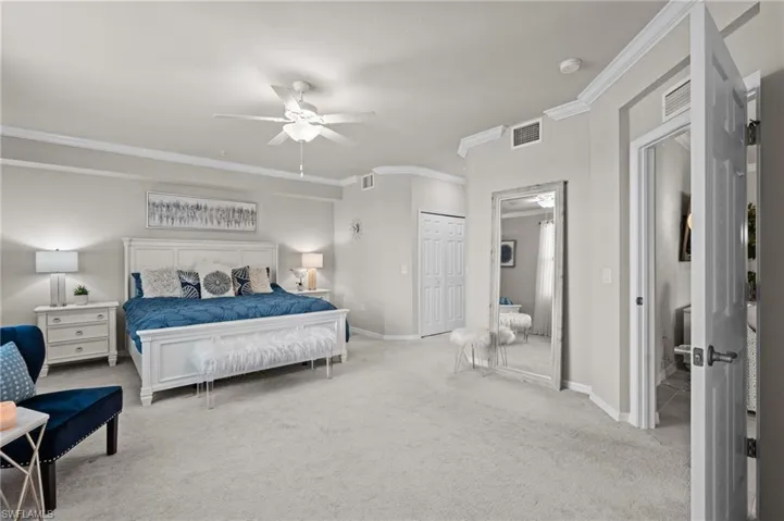 Carpeted bedroom with a ceiling fan, crown molding, baseboards, and visible vents