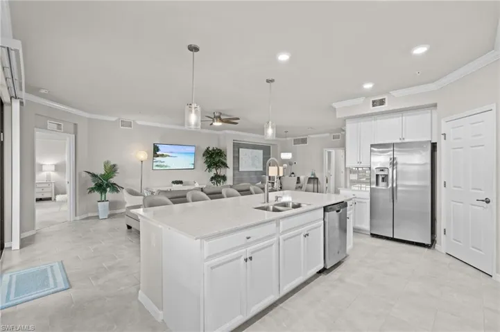 Kitchen featuring a sink, a ceiling fan, stainless steel appliances, a kitchen island with sink, and visible vents