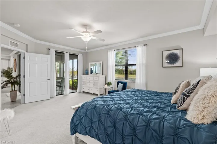 Carpeted bedroom featuring multiple windows, crown molding, access to outside, and visible vents