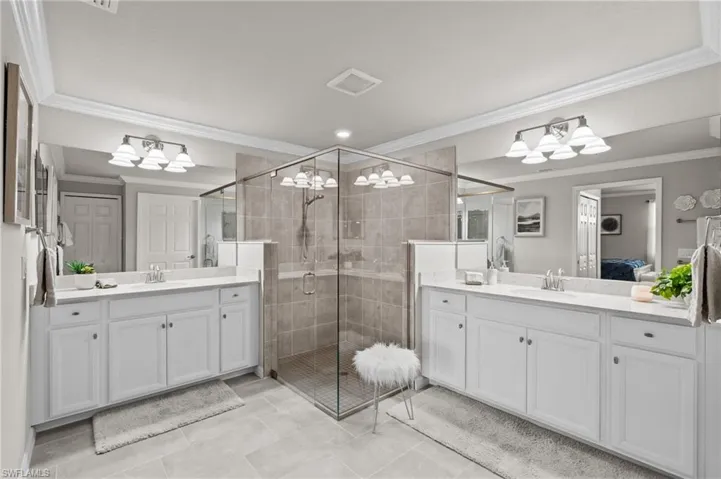 Bathroom featuring crown molding, a sink, a shower stall, ensuite bathroom, and visible vents
