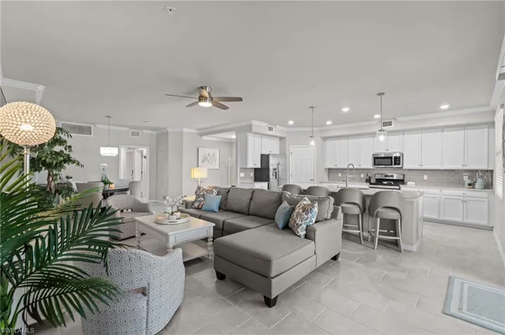 Living room with crown molding, visible vents, recessed lighting, and a ceiling fan