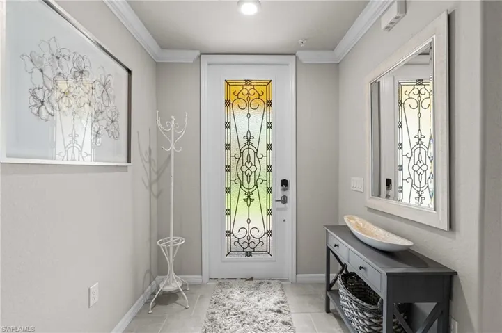 Entrance foyer featuring baseboards, crown molding, and tile patterned floors