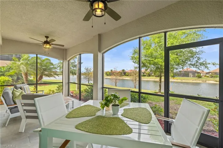 Sunroom / solarium with a water view, ceiling fan, and a textured wall