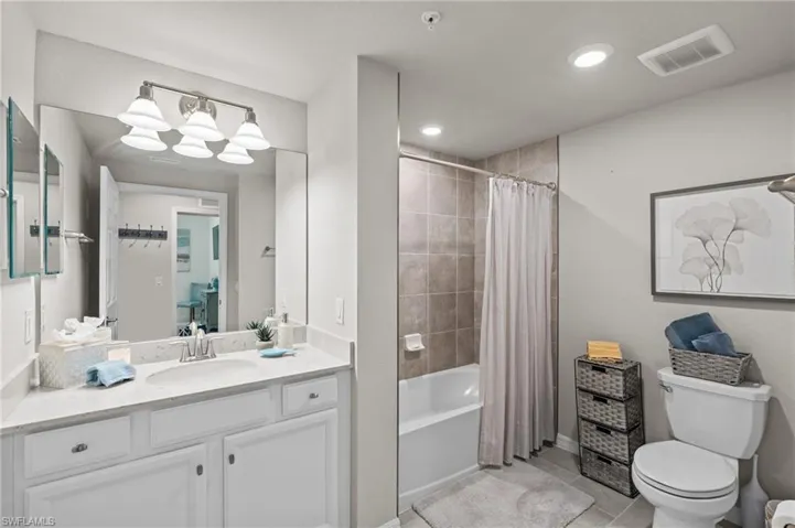Bathroom with tile patterned flooring, vanity, shower / tub combo with curtain, toilet, and visible vents