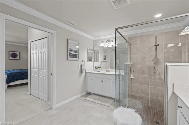 Full bathroom featuring vanity, visible vents, a stall shower, and crown molding
