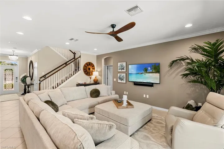 Living area featuring ornamental molding, recessed lighting, ceiling fan, arched walkways, and light tile patterned flooring