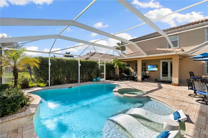 View of swimming pool featuring a patio, a sunroom, glass enclosure, and a pool with connected hot tub