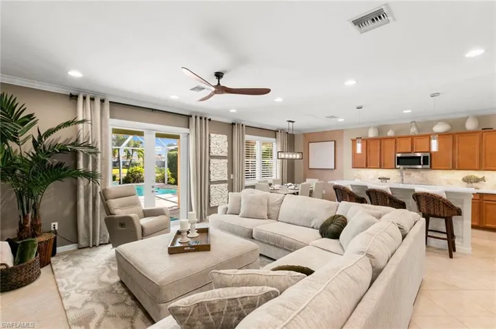 Living room with light tile patterned floors, ornamental molding, recessed lighting, and a ceiling fan