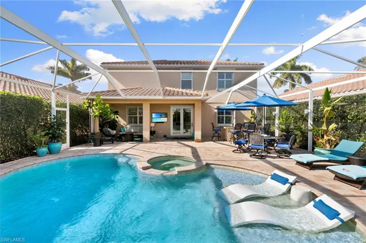 View of pool featuring a sunroom, a patio area, glass enclosure, and a pool with connected hot tub
