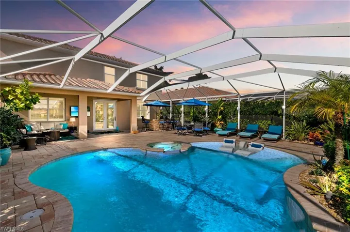 Pool at dusk with a sunroom, a patio area, a lanai, an outdoor living space, and french doors