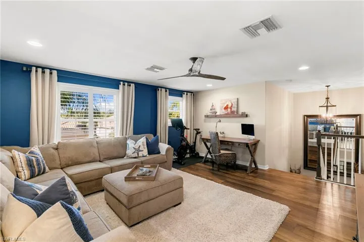 Living room featuring wood finished floors, recessed lighting, an office area, ceiling fan, and a chandelier