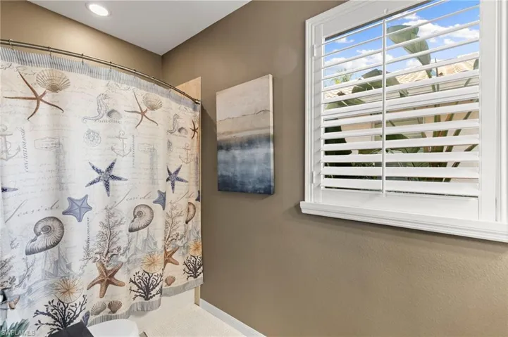 Bathroom with a shower with shower curtain and baseboards