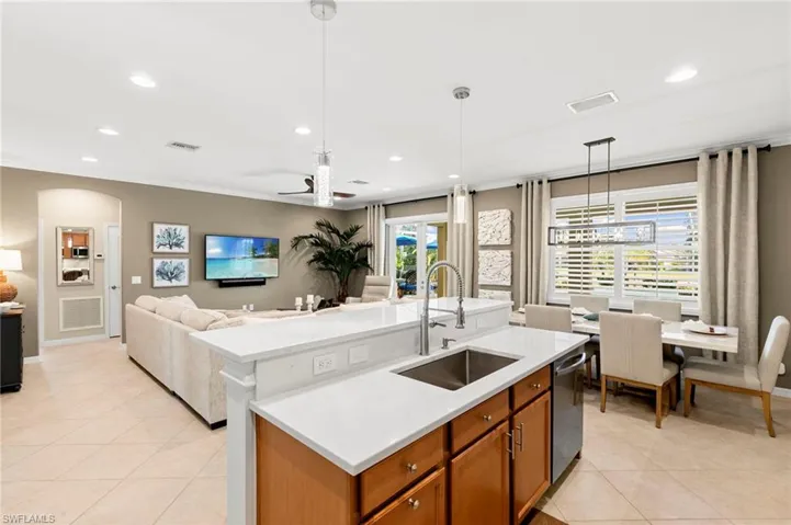 Kitchen with hanging light fixtures, recessed lighting, brown cabinets, a center island with sink, and light tile patterned floors