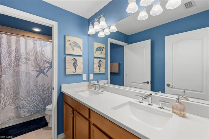 Full bathroom with double vanity and light tile patterned floors