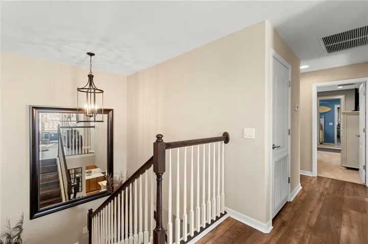 Corridor with an upstairs landing, dark wood-type flooring, and a chandelier
