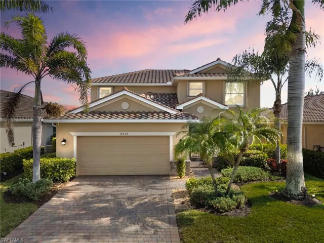 Mediterranean / spanish-style house featuring a tiled roof, decorative driveway, stucco siding, a garage, and a yard