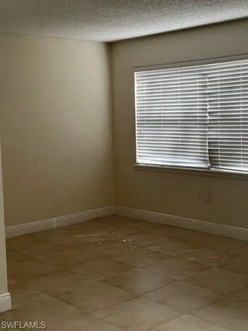Unfurnished room with baseboards and a textured ceiling