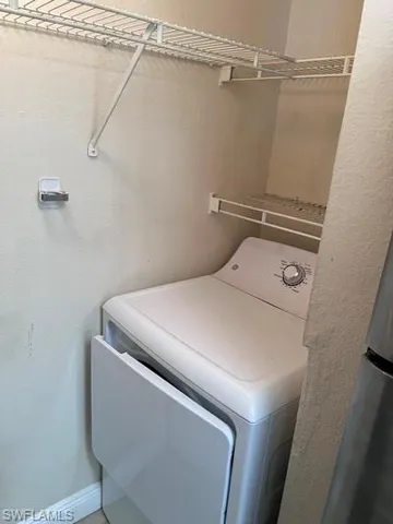 Laundry area with a textured wall and washer / clothes dryer