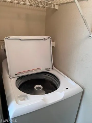 Laundry view of washer / clothes dryer and a textured wall