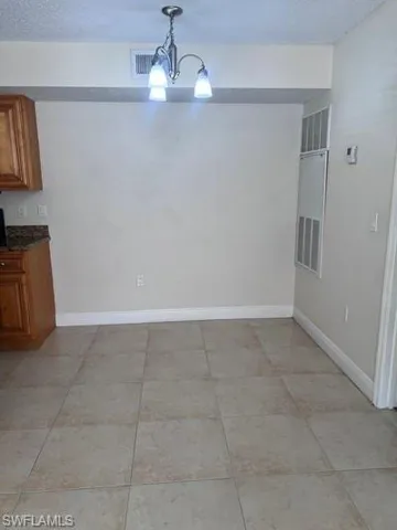 Unfurnished dining area with a textured ceiling, a heating unit, and light tile patterned floors