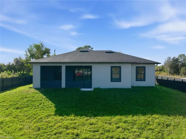 Rear view of property featuring a fenced backyard, stucco siding, and roof with shingles