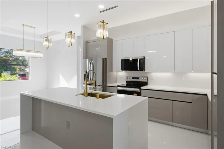 Kitchen featuring modern cabinets, stainless steel appliances, pendant lighting, white cabinets, and an island with sink
