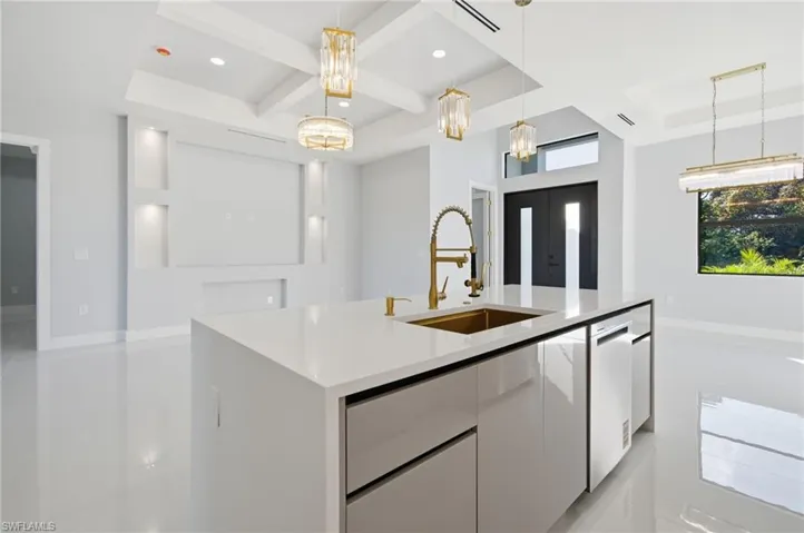 Kitchen featuring white cabinets, modern cabinets, coffered ceiling, light stone countertops, and decorative light fixtures