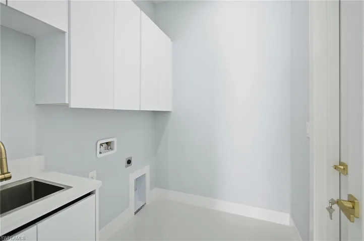Washroom featuring electric dryer hookup, hookup for a washing machine, cabinet space, and light tile patterned floors