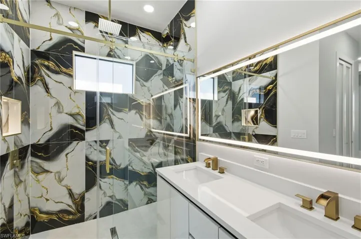 Full bath featuring a marble finish shower and double vanity