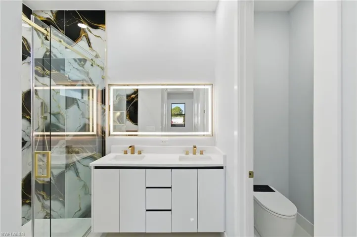 Bathroom featuring a marble finish shower and double vanity